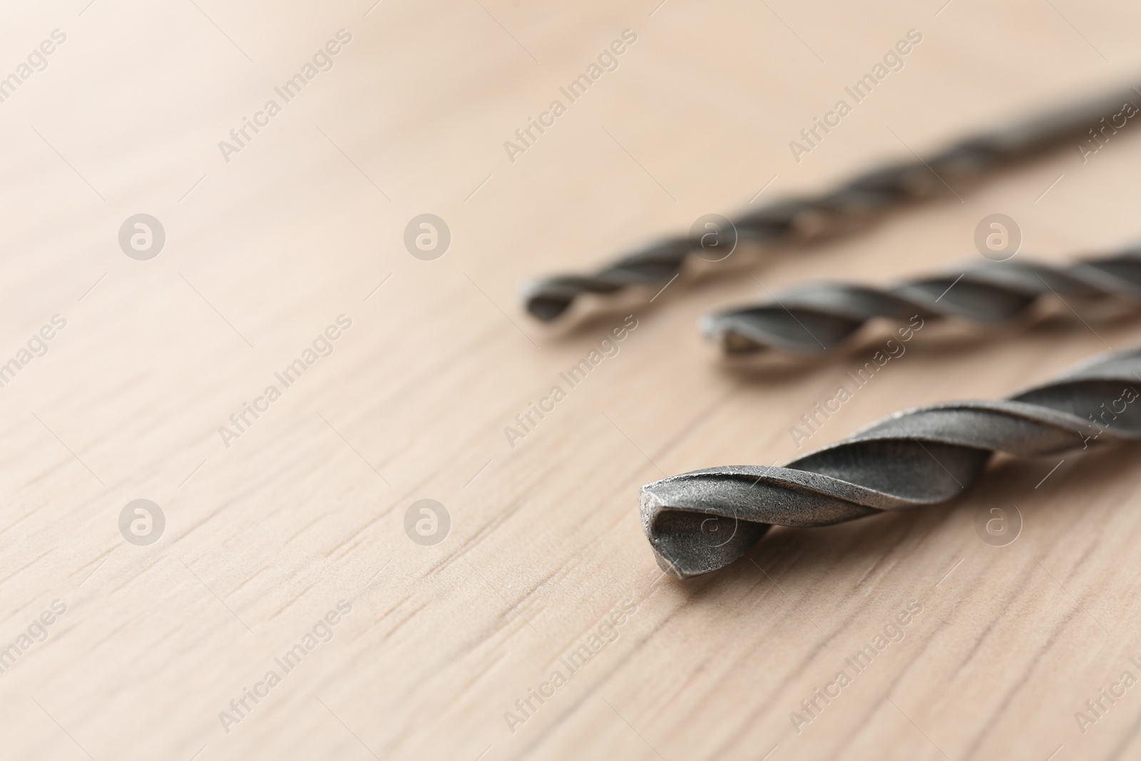 Photo of Different drill bits on wooden surface, closeup. Space for text