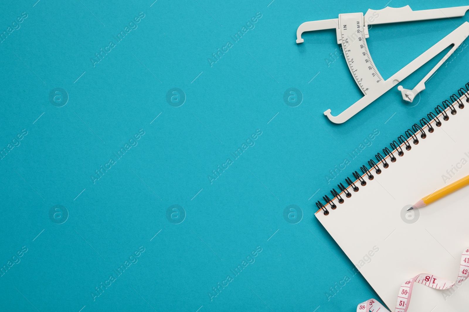 Photo of Body fat caliper, measuring tape, notebook and pencil on light blue background, flat lay. Space for text