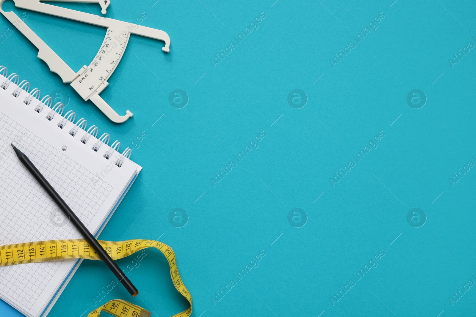 Photo of Body fat caliper, measuring tape, notebook and pencil on light blue background, flat lay. Space for text