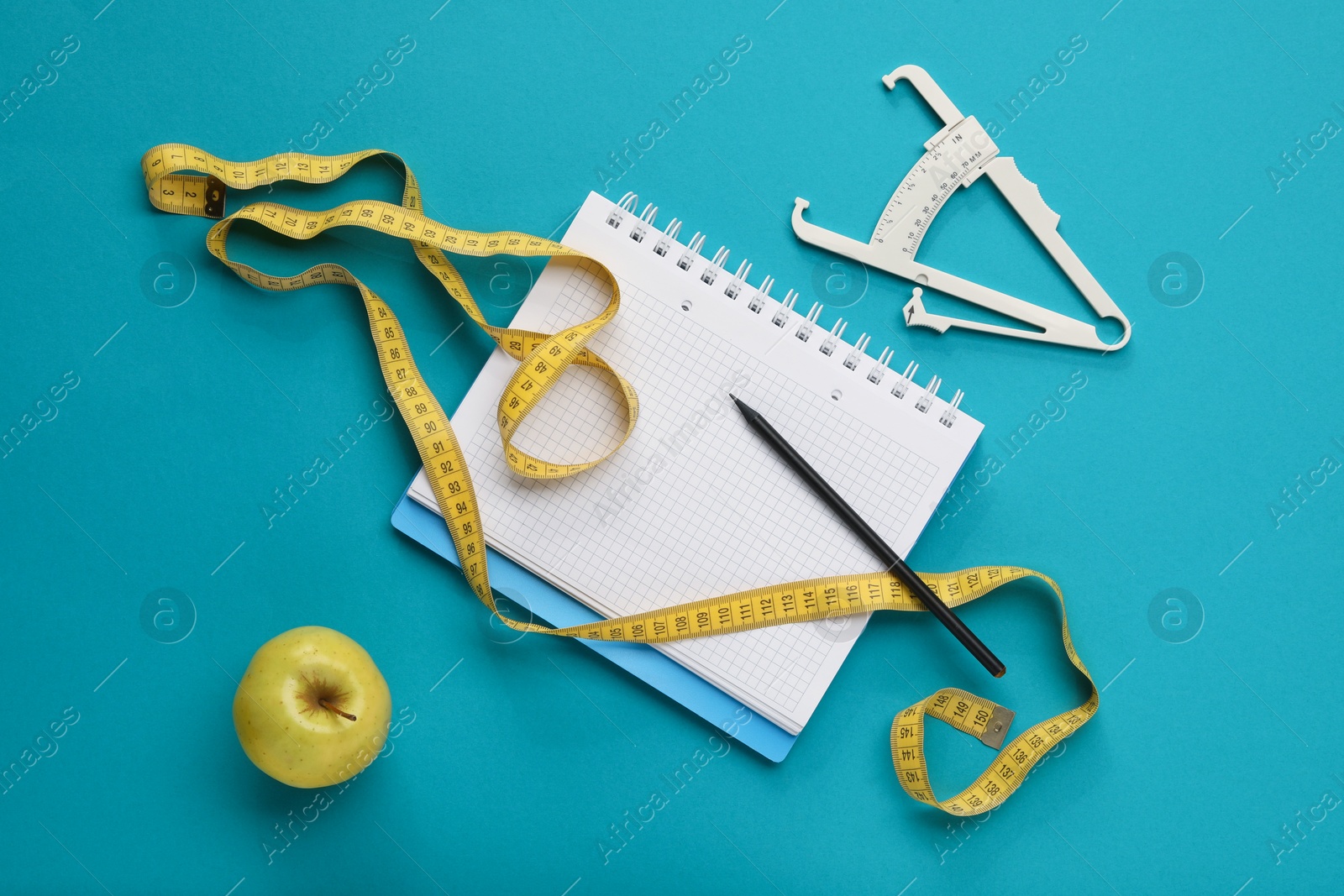 Photo of Flat lay composition with body fat caliper, measuring tape and notebook on light blue background