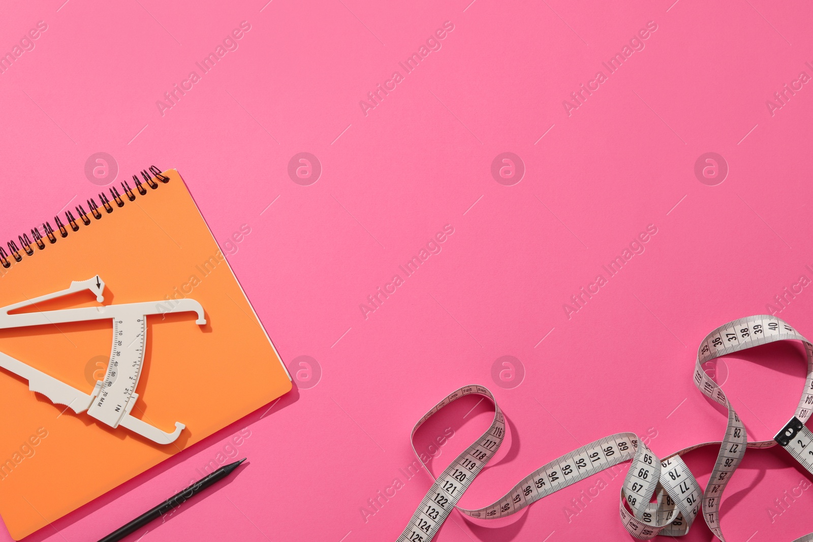 Photo of Body fat caliper, measuring tape, notebook and pencil on pink background, flat lay. Space for text