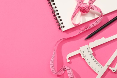 Photo of Body fat caliper, measuring tape, notebook and pencil on pink background, flat lay. Space for text