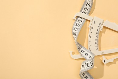 Photo of Plastic body fat caliper and measuring tape on beige background, top view. Space for text