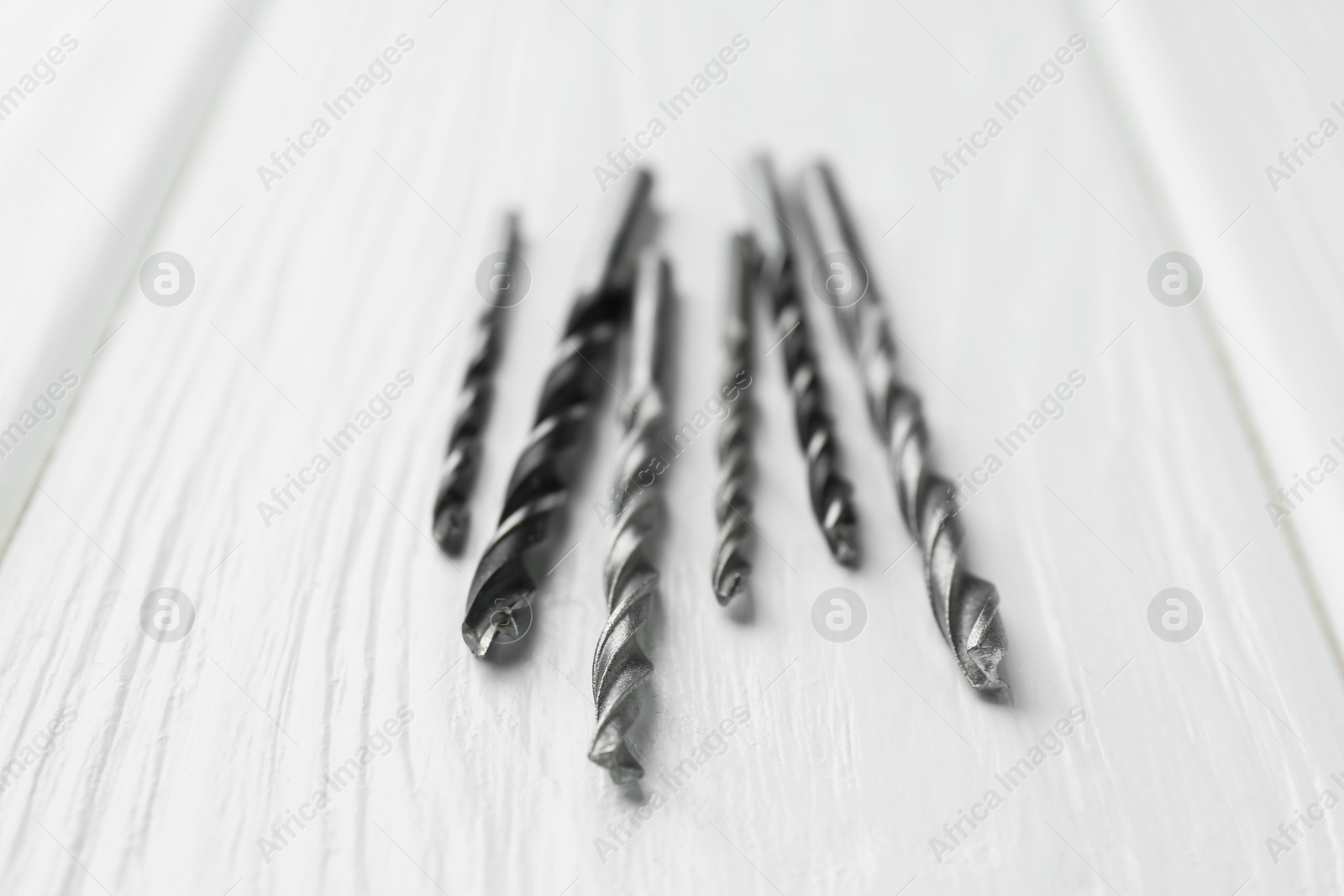 Photo of Many different drill bits on white wooden table