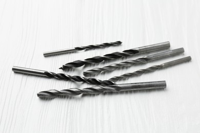 Photo of Many different drill bits on white wooden table