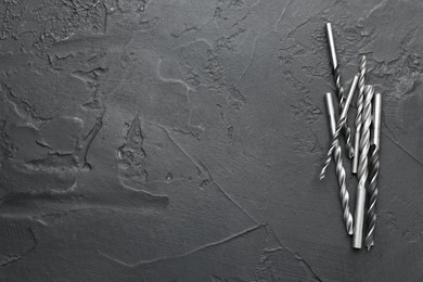 Photo of Many different drill bits on black table, top view. Space for text