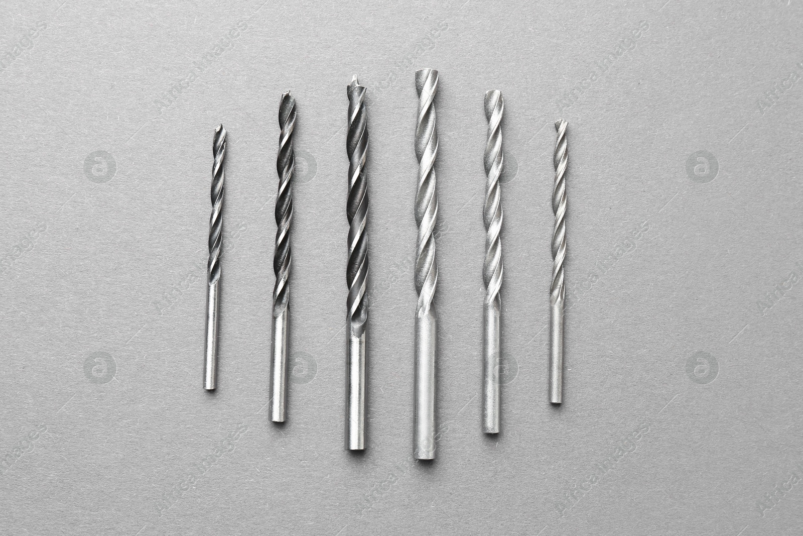 Photo of Many different drill bits on light grey table, top view