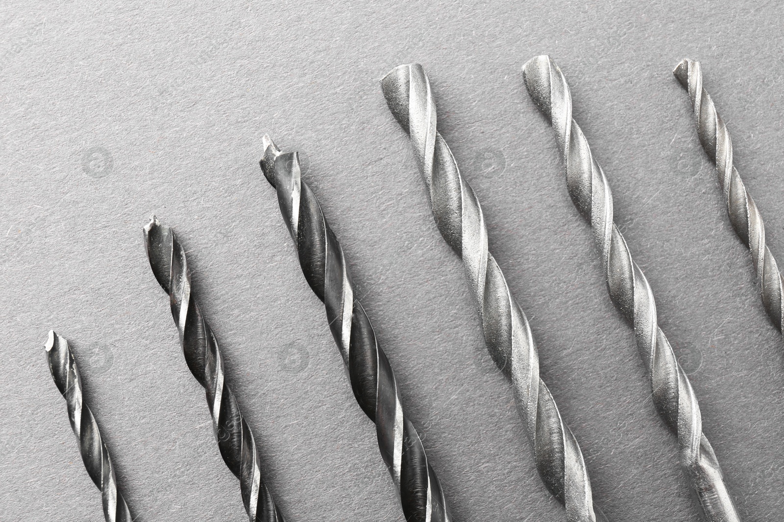 Photo of Many different drill bits on light grey table, top view