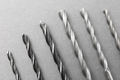 Photo of Many different drill bits on light grey table, top view