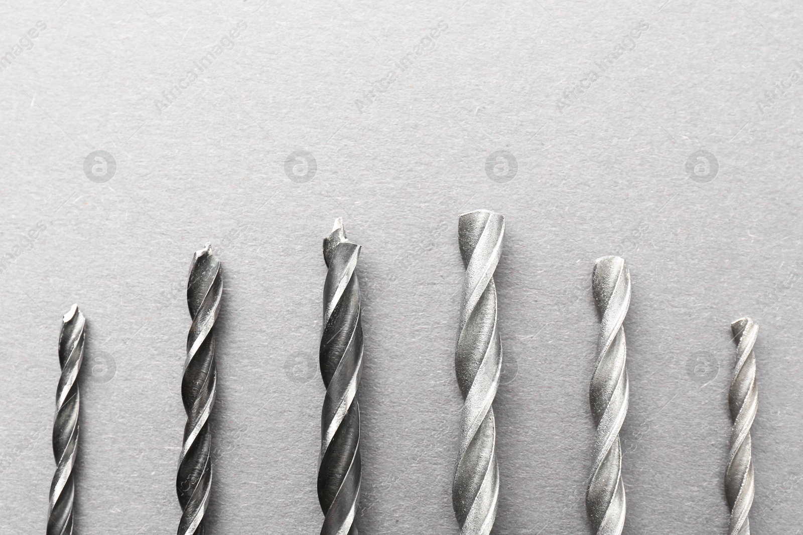 Photo of Many different drill bits on light grey table, top view