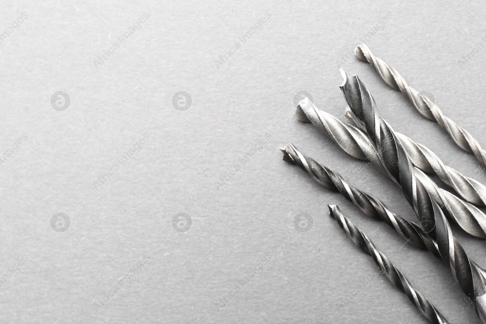 Photo of Many different drill bits on light grey table, above view. Space for text