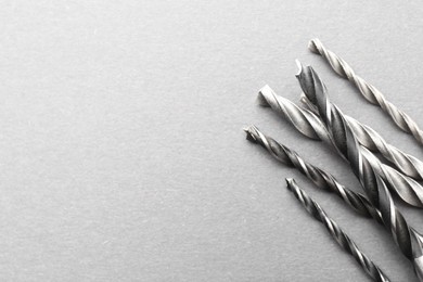 Photo of Many different drill bits on light grey table, above view. Space for text