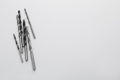 Photo of Many different drill bits on light grey background, top view. Space for text