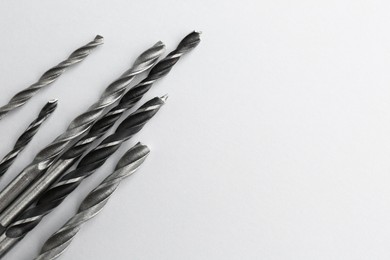 Many different drill bits on light grey background, top view. Space for text