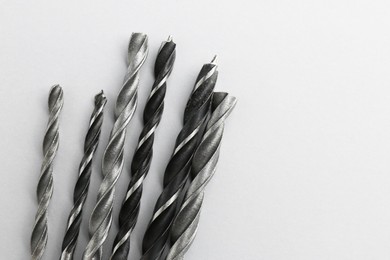 Photo of Many different drill bits on light grey background, top view. Space for text