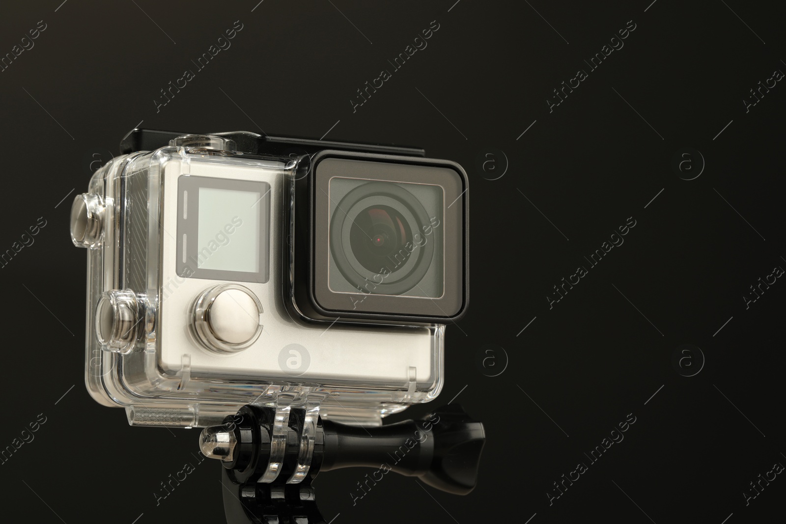 Photo of Modern action camera and mount against black background, closeup. Space for text