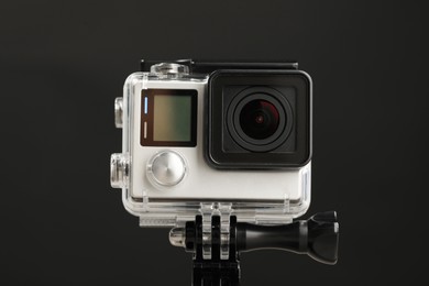 Photo of Modern action camera and mount against black background, closeup