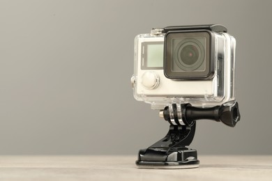 Modern action camera and mount on table against grey background. Space for text