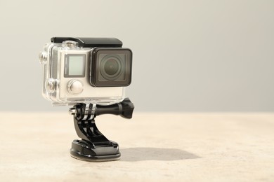 Modern action camera and mount on table against grey background. Space for text