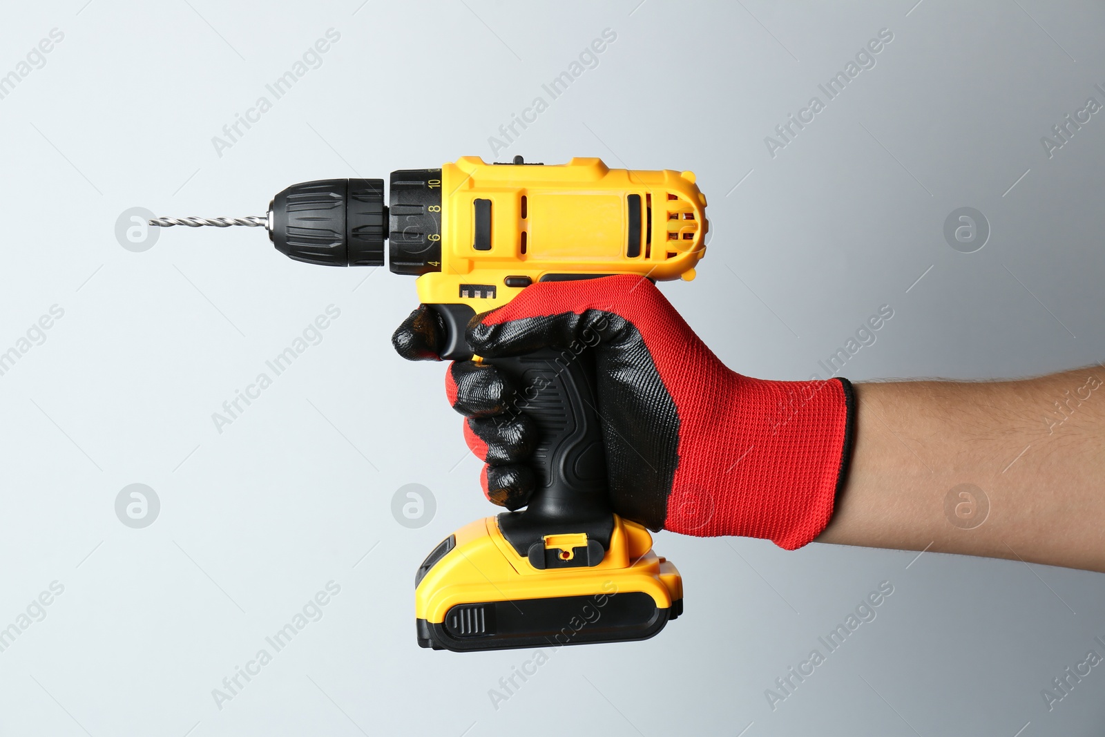 Photo of Man with cordless electric drill on light background, closeup