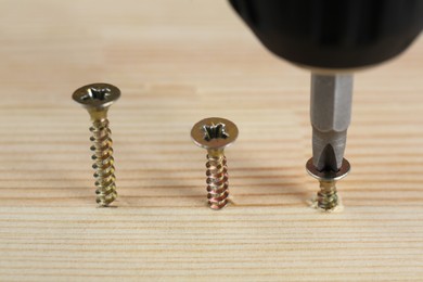 Photo of Screwing screw into wooden plank, closeup view