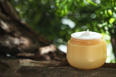 Photo of Stylish presentation of facial cream in jar outdoors, closeup. Space for text