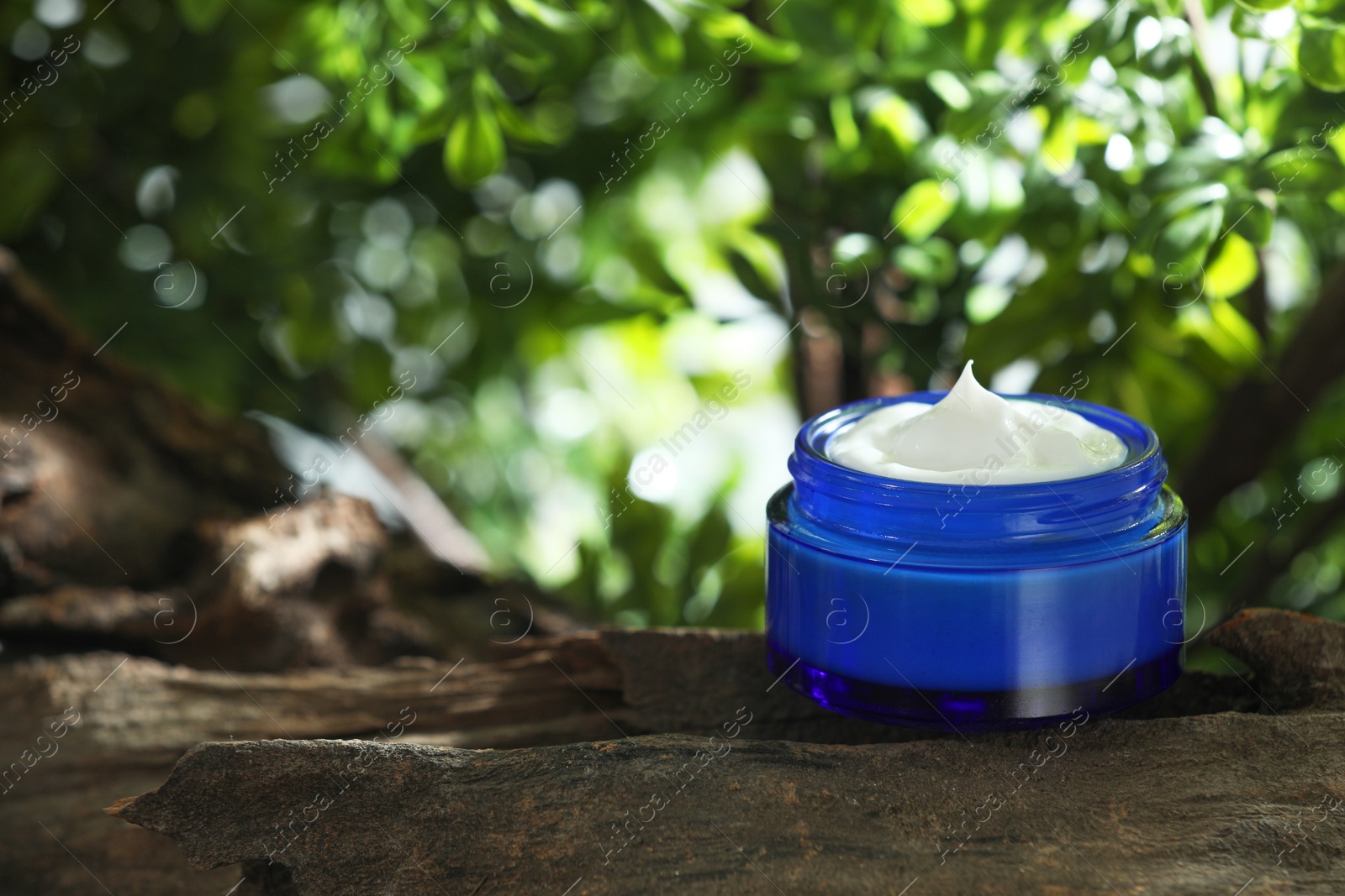 Photo of Stylish presentation of facial cream in jar outdoors. Space for text