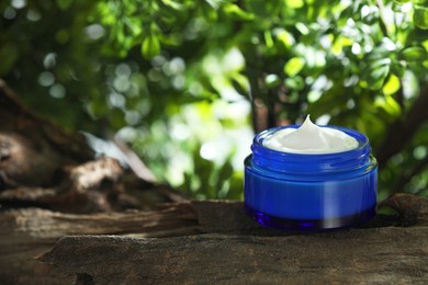 Photo of Stylish presentation of facial cream in jar outdoors. Space for text