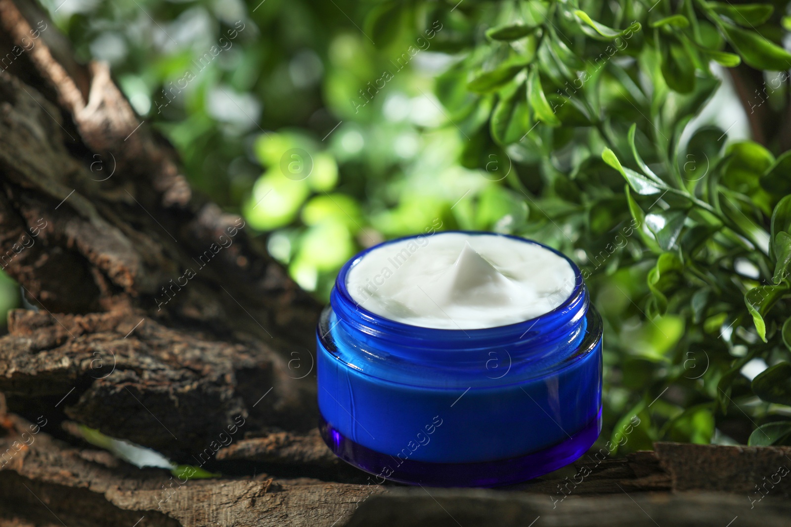 Photo of Stylish presentation of facial cream in jar outdoors, closeup