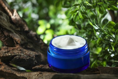 Photo of Stylish presentation of facial cream in jar outdoors, closeup