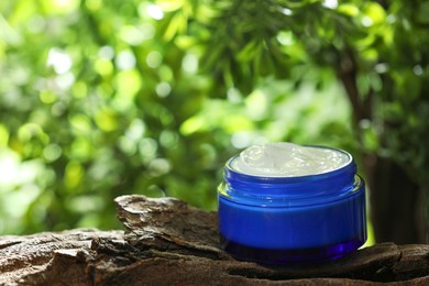 Photo of Stylish presentation of facial cream in jar outdoors, closeup. Space for text