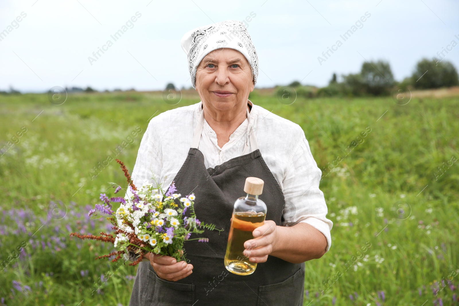 Photo of Senior woman with tincture and wildflowers outdoors