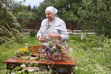 Senior woman making tincture at table outdoors