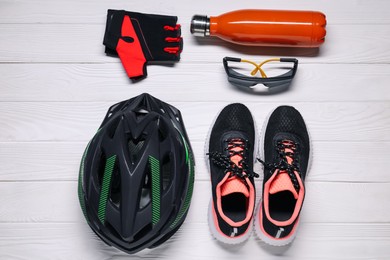 Photo of Bicycle helmet, sneakers, thermo bottle, fingerless gloves and goggles on white wooden background, flat lay