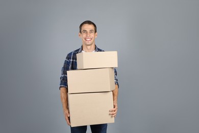 Photo of Moving into new house. Man with cardboard boxes on grey background