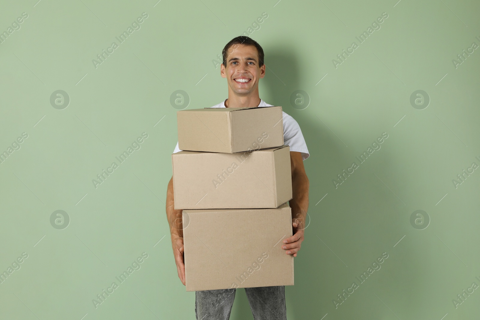 Photo of Moving into new house. Man with cardboard boxes on light green background