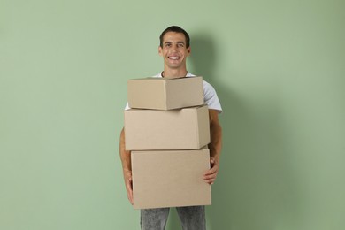 Moving into new house. Man with cardboard boxes on light green background