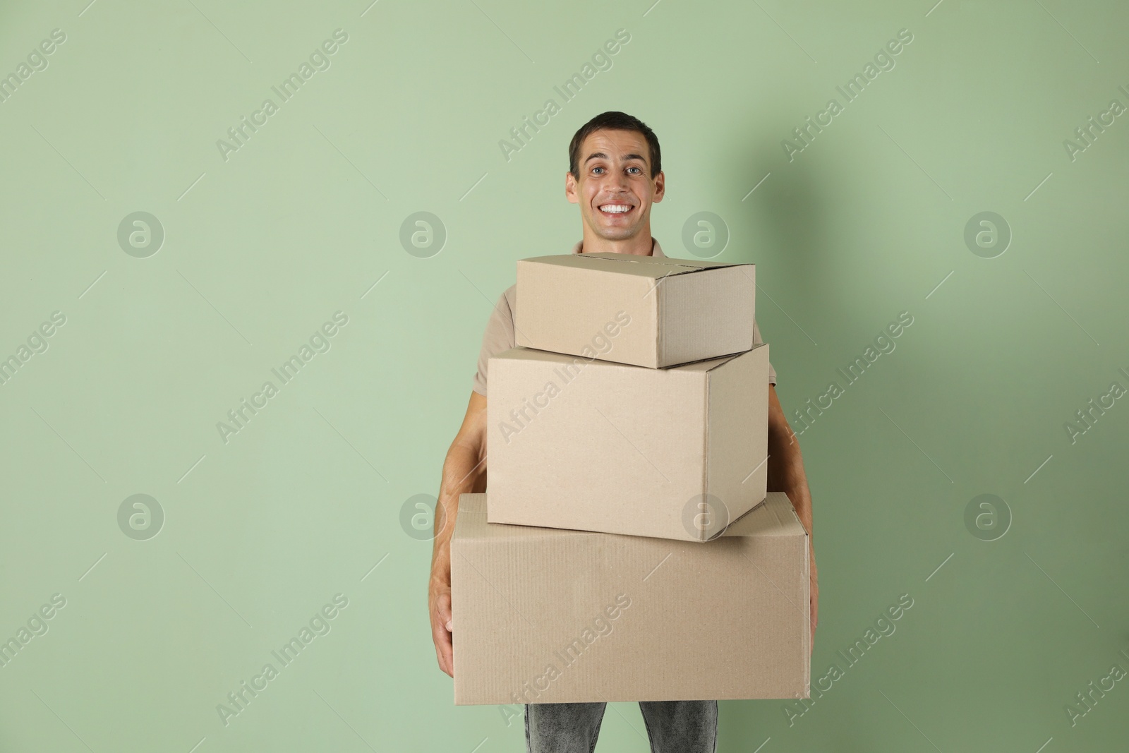 Photo of Moving into new house. Man with cardboard boxes on light green background