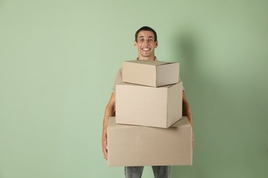 Moving into new house. Man with cardboard boxes on light green background