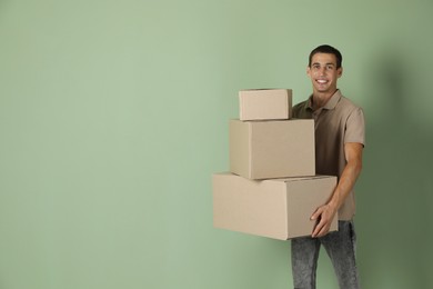 Moving into new house. Man with cardboard boxes on light green background, space for text