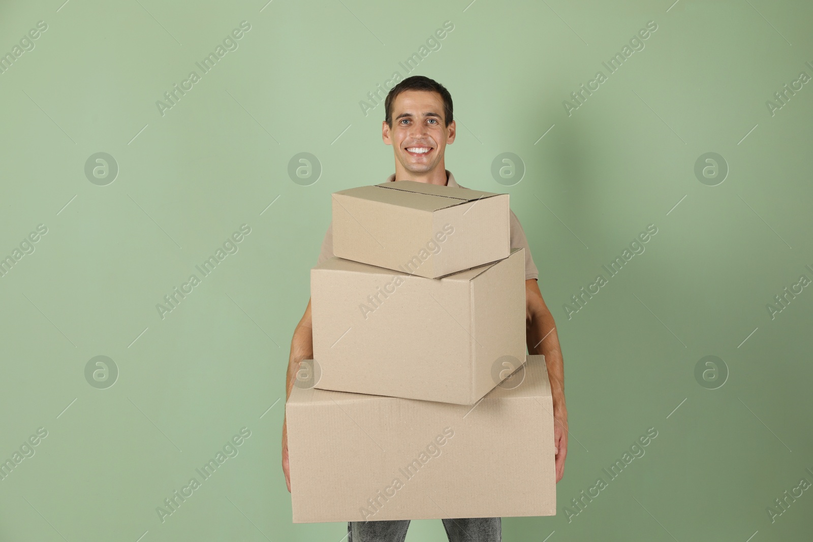 Photo of Moving into new house. Man with cardboard boxes on light green background