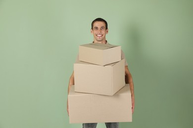 Moving into new house. Man with cardboard boxes on light green background