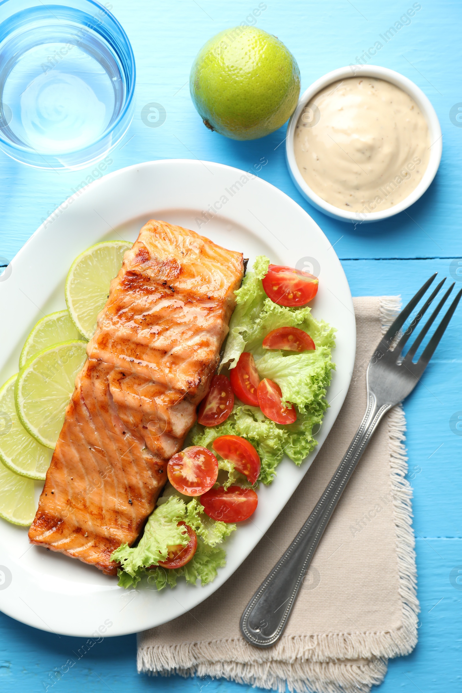 Photo of Delicious grilled salmon fillet served on light blue wooden table, flat lay