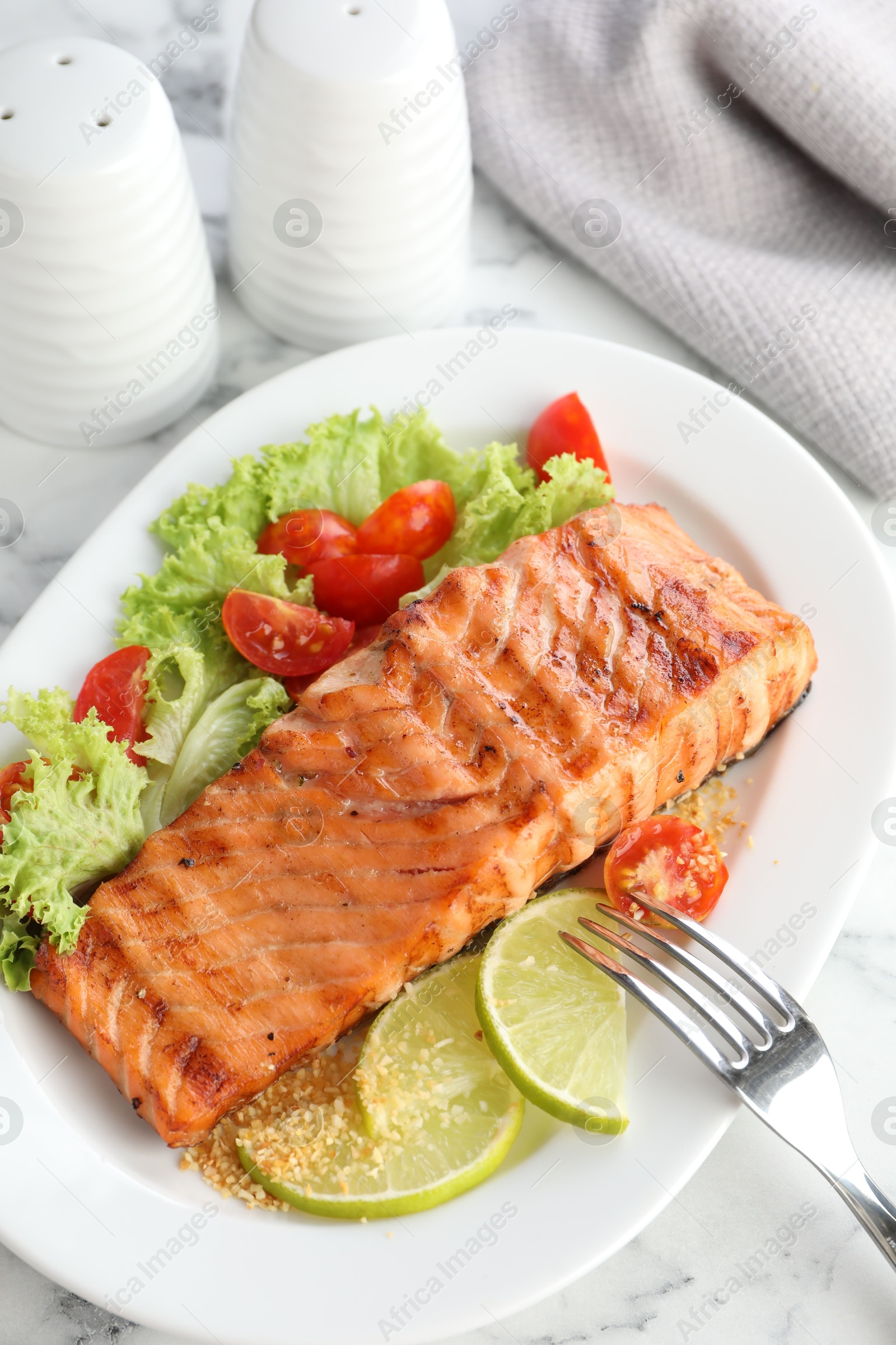 Photo of Delicious grilled salmon fillet served on white marble table, above view