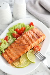 Photo of Delicious grilled salmon fillet served on white marble table, above view