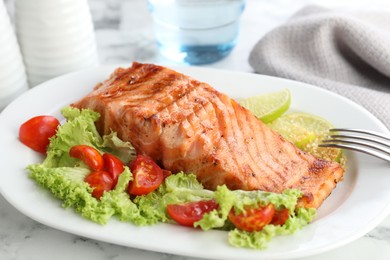 Delicious grilled salmon fillet served on white marble table, closeup