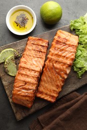 Photo of Delicious grilled salmon fillets served on grey table, flat lay