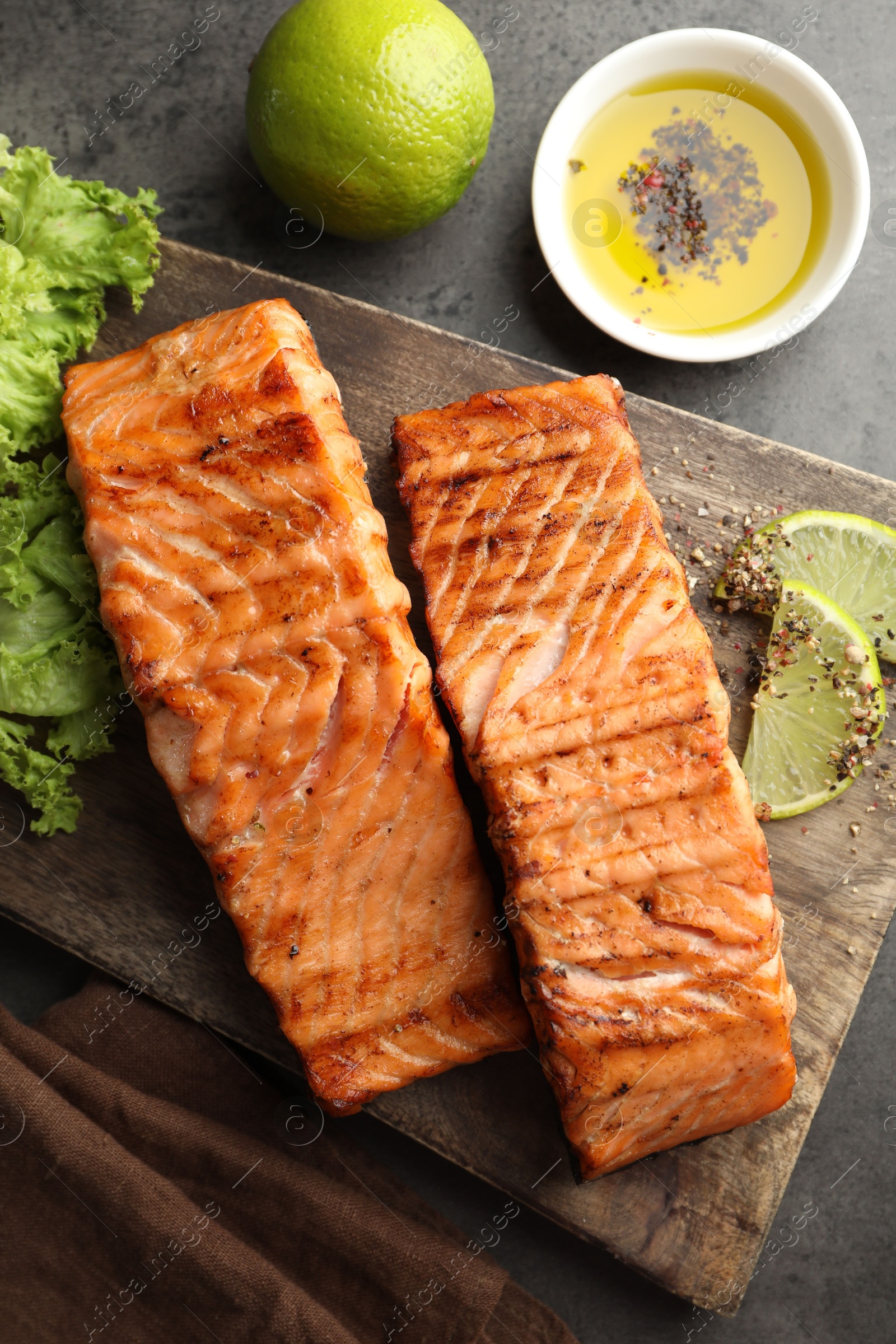 Photo of Delicious grilled salmon fillets served on grey table, flat lay