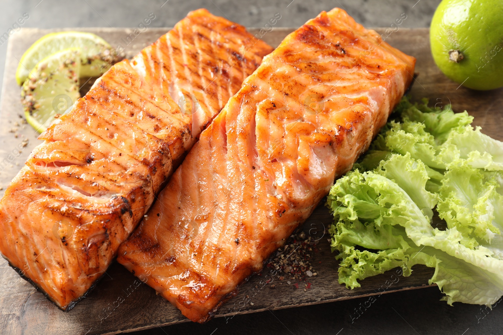 Photo of Delicious grilled salmon fillets served on grey table, closeup