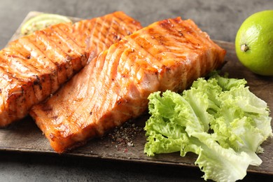 Delicious grilled salmon fillets served on grey table, closeup